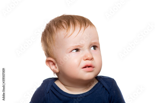 Portrait of a disgruntled child looking incredulously to the side with frowning eyebrows, close-up of a toddler isolated on a white background. photo