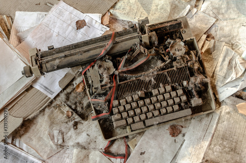 A vintage brown beige broken typewriter on a pile of paper