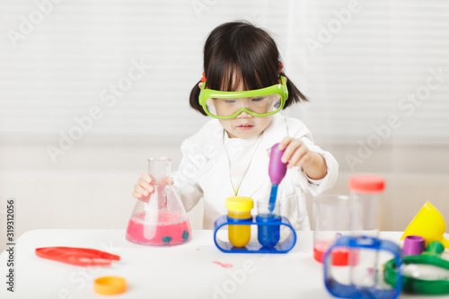 toddler girl pretend play  scientist  role  at home against white background