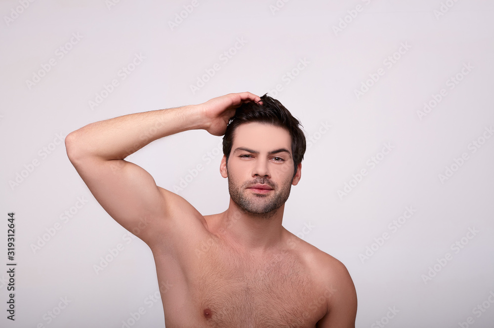 Caucasian male looking directly at camera and holding his hand on his hair Caucasian male looking directly at camera and holding his hand on his hair