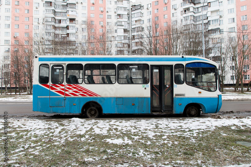 Blue and white bus stands on the side of the road