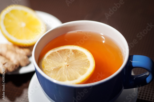cup of ginger tea, ginger root and lemon on a wooden table. natural treatment for colds and flu during the winter season