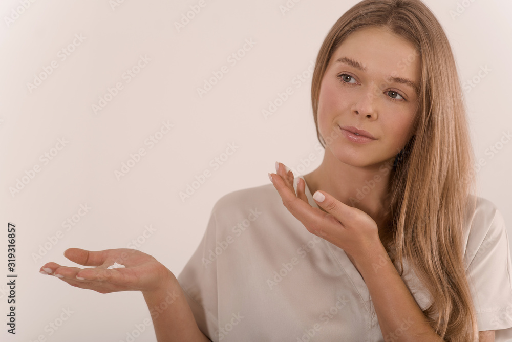 Portrait of a young beautiful woman with a drop of cream on her palm. Portrait of a young beautiful woman with a drop of cream on her palm.