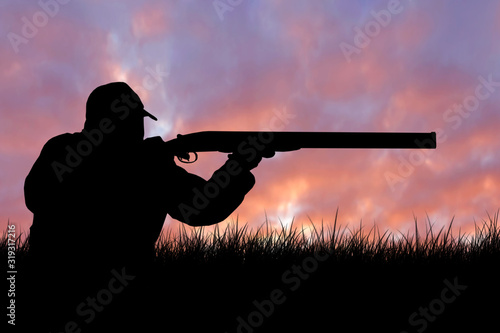 Obraz na płótnie Silhouette of a hunter with a gun in the reeds against the sun, an ambush for du
