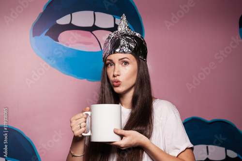 Woman wearing tinfoil hat and holding a cup photo