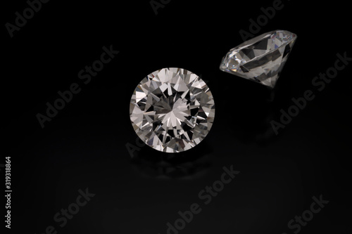 Foto A solitaire faceted, round diamond sits on a black background