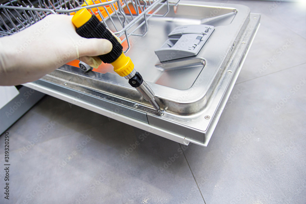 repair of a modern dishwasher with screwdrivers in the kitchen