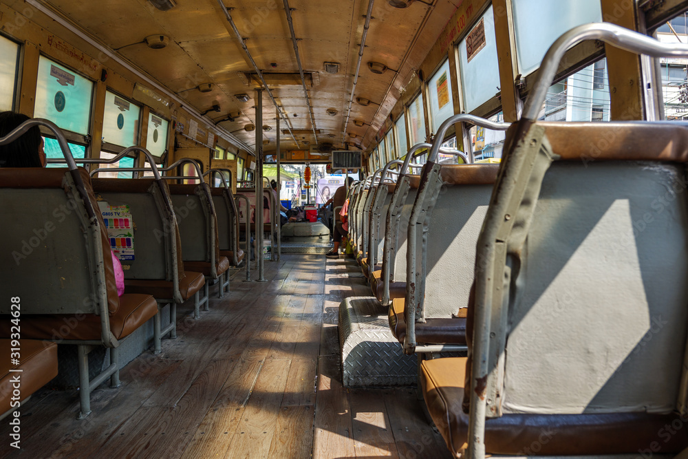 Obraz premium Interior view of corridor between row of seats in old local hot public transportation bus without air condition in Bangkok, Thailand.