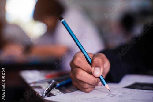Hand of Student doing test or exam in classroom of school with stress