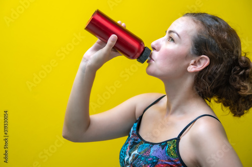 Blonde and Brazilian woman on a yellow background drinking water