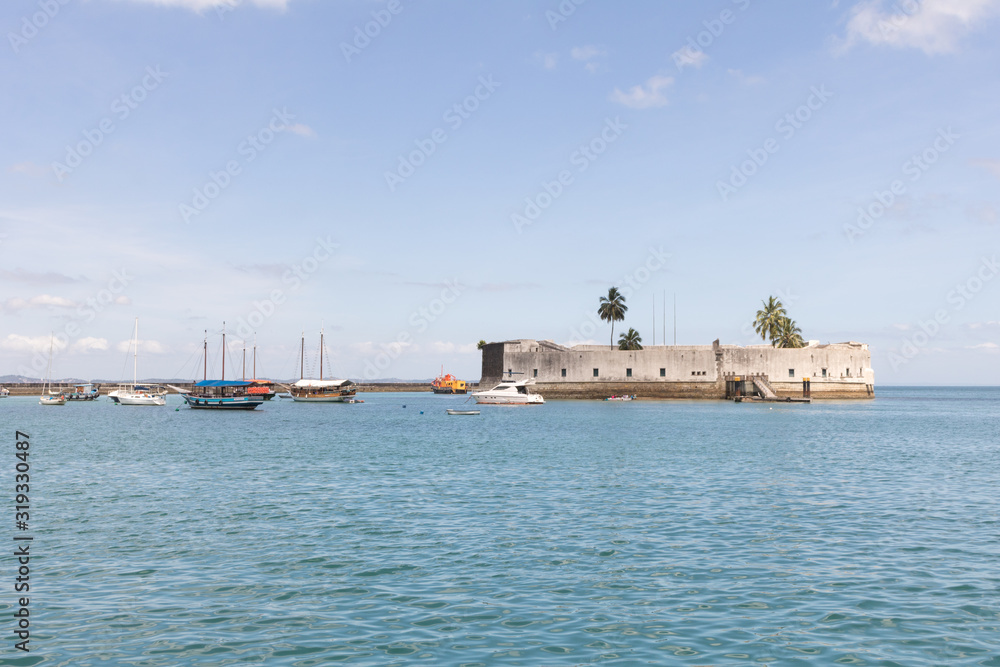Salvador, Brazil - January 2020: View of Sao Marcelo Fort, boats, blue sea and clear sky.