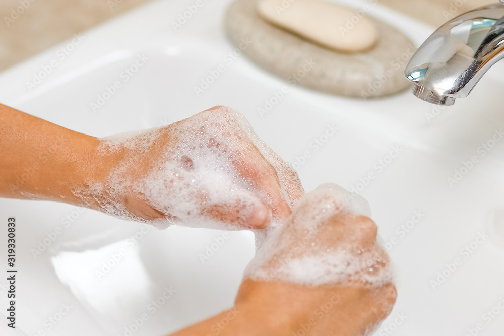 Fototapeta premium a Washing hands with soap under the faucet with water