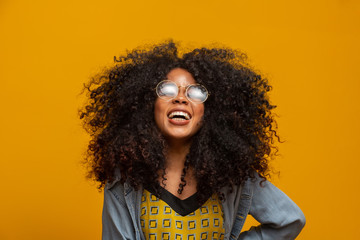 Beauty portrait of african american with glasses and afro hairstyle on a yellow background. Brazilian young woman.