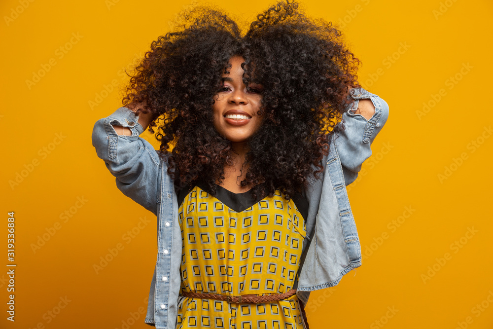 Beauty portrait of african american woman with afro hairstyle and glamour makeup. Brazilian woman. Mixed race. Curly hair. Hair style. Yellow background. Beauty portrait of african american woman with afro hairstyle and glamour makeup. Brazilian woman. Mixed race. Curly hair. Hair style. Yellow background.