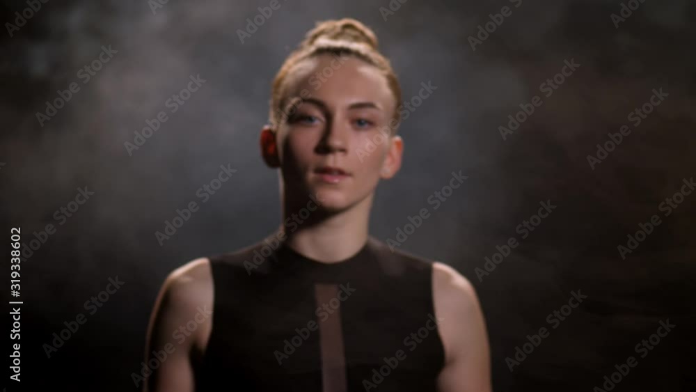 Close-up portrait of attractive female dancer in emotional performance of modern contemporary choreography. Young artist in black body dancing with expression in darkness of smoky dance studio Close-up portrait of attractive female dancer in emotional performance of modern contemporary choreography. Young artist in black body dancing with expression in darkness of smoky dance studio