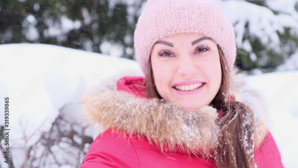 Smiling young woman in red jacket throwing snow in the air on a sunny winter day. Smiling young woman in red jacket throwing snow in the air on a sunny winter day.