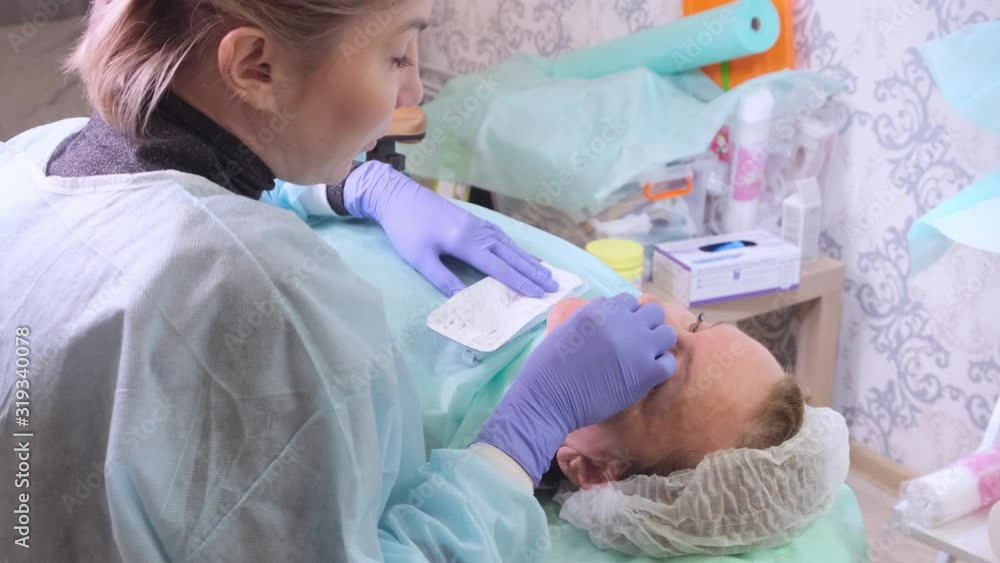 Middle aged woman 50 getting a lifting injection of an injection of hyaluronic acid into the face by a doctor cosmetologist. Cosmetic procedure. Middle aged woman 50 getting a lifting injection of an injection of hyaluronic acid into the face by a doctor cosmetologist. Cosmetic procedure.