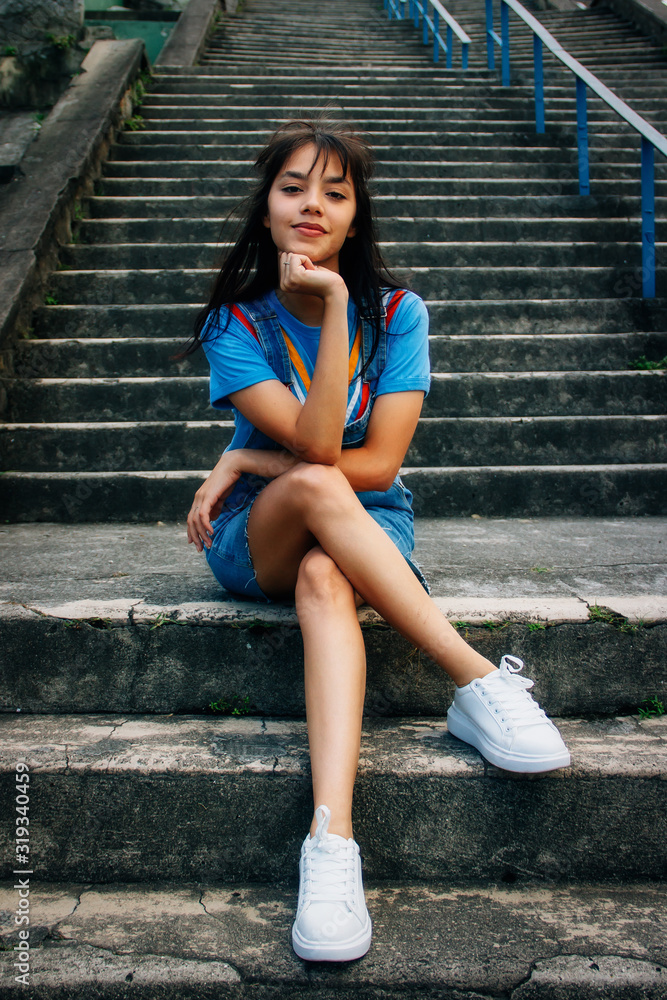 Obraz premium Girl in blue clothes cross-legged sitting on a staircase