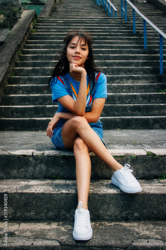 Girl in blue clothes cross-legged sitting on a staircase © leotx