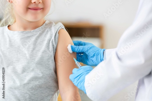 Doctor vaccinating little g...