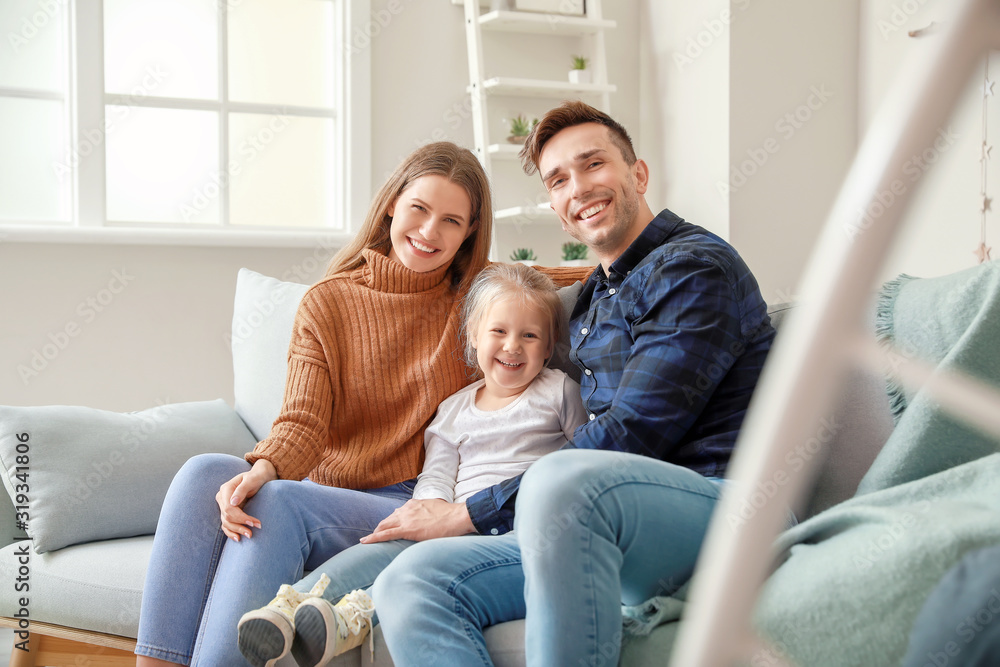 Happy young family sitting on sofa at home