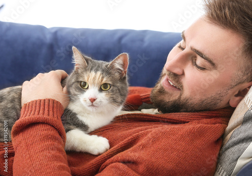 Man with cute cat lying on ...