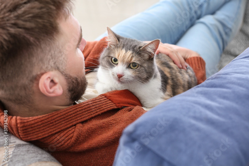 Man with cute cat lying on ...