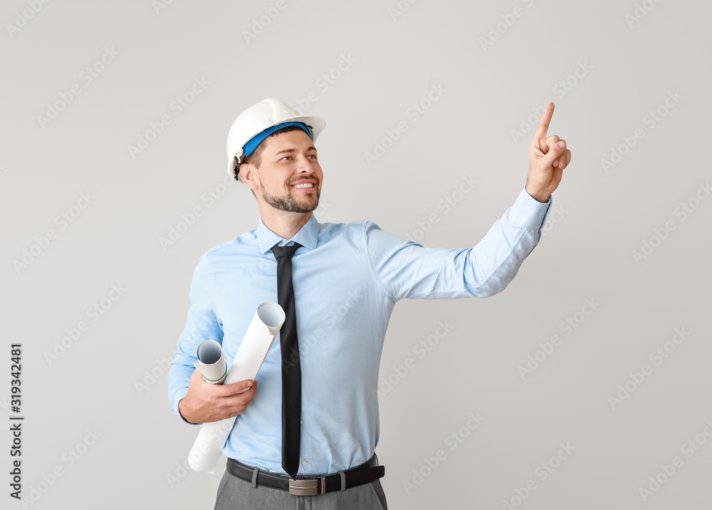 Male engineer showing something on light background Male engineer showing something on light background