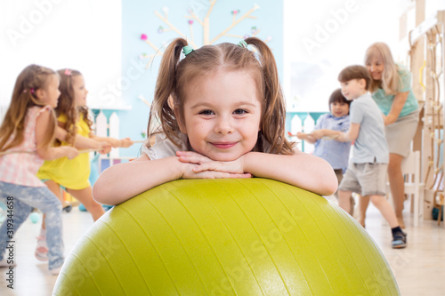 Children in the gym. Preschool kid girl with fitball in physical education lesson.