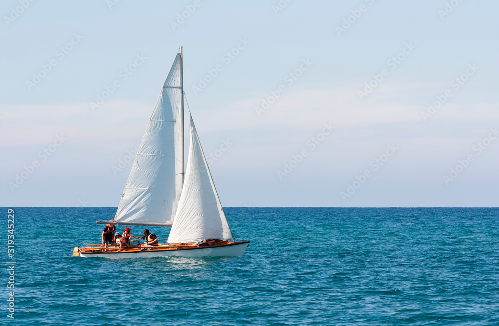 A sailboat with a group of people in life jackets is floating in the sea