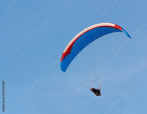 Paraglider is flying against the blue sky