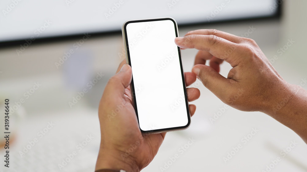 Close up view of male freelancer typing smartphone while sitting in workspace Close up view of male freelancer typing smartphone while sitting in workspace