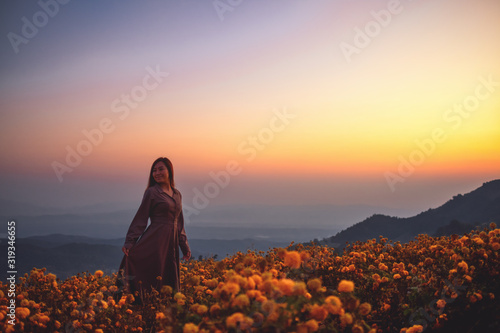 A woman standing among beautiful flower garden on the top of the hill before sunrise