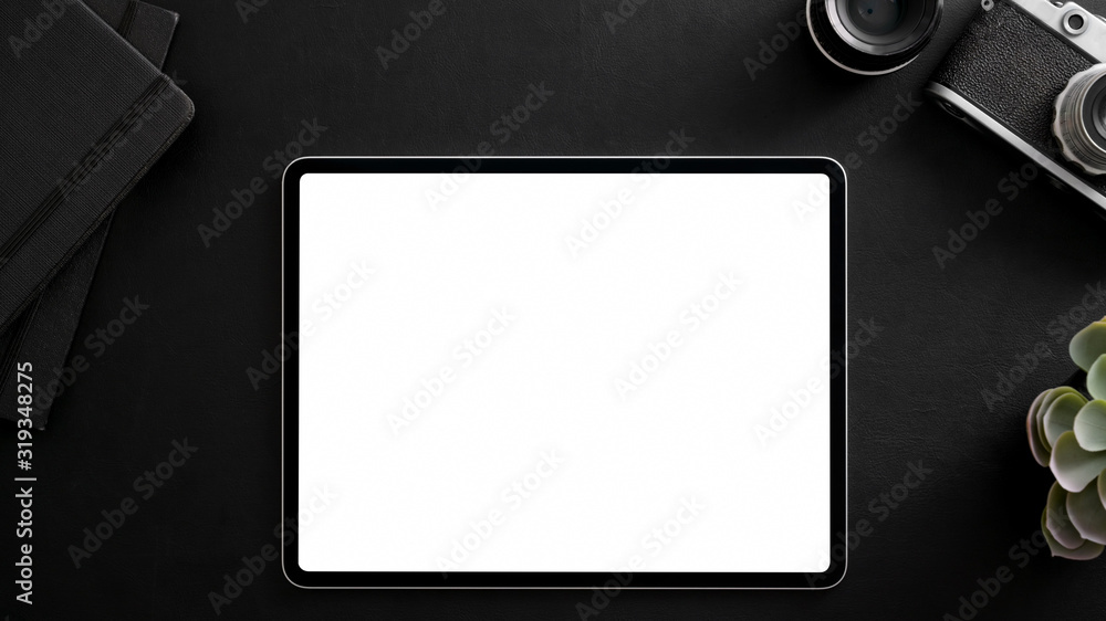 Top view of photographer workplace with blank screen tablet, camera, office supplies and decorations Top view of photographer workplace with blank screen tablet, camera, office supplies and decorations
