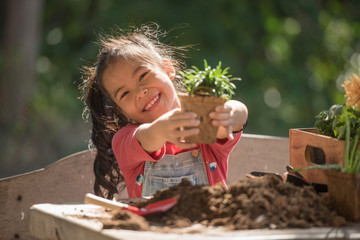 adorable asian little girl is planting spring flowers tree in pots in garden outside house, child education of nature. caring for new life. earth day holiday concept. world environment day. ecology.