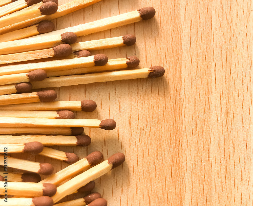 many wooden matches lie on a wooden background. flammable matches on a wooden table. many wooden matches lie on a wooden background. flammable matches on a wooden table.