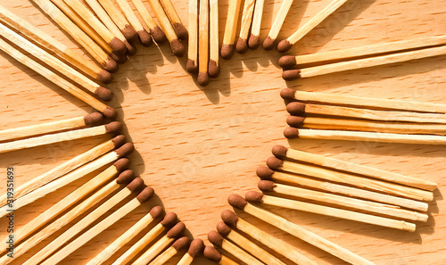 Wooden safety matches on a wooden background arranged in the shape of a heart. matchsticks in the shape of a heart for matchday celebrations.