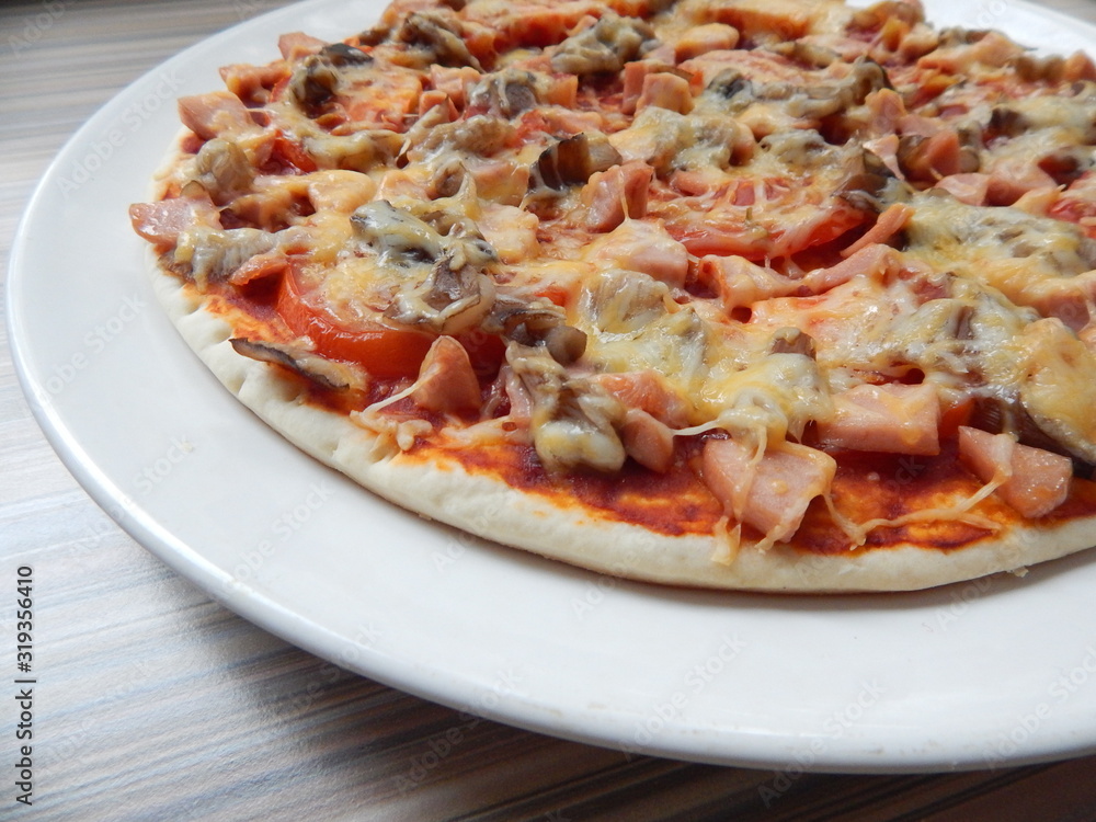 ready hot pizza with ham, mushrooms and cheese on a white plate ready hot pizza with ham, mushrooms and cheese on a white plate