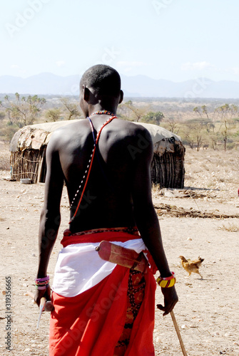 AFRICA, KENYA, MASAI MARA NATIONAL RESERVE, AUGUST 3, 2010: Masai village with masai tribe. Back of a masai warrior, portrait of a masai warrior backwards, masa village.