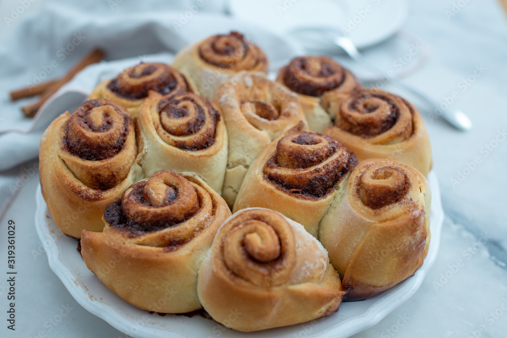Cinnamon rolls with sugar frosting. With cinnamon sticks and spices, wooden background Cinnamon rolls with sugar frosting. With cinnamon sticks and spices, wooden background