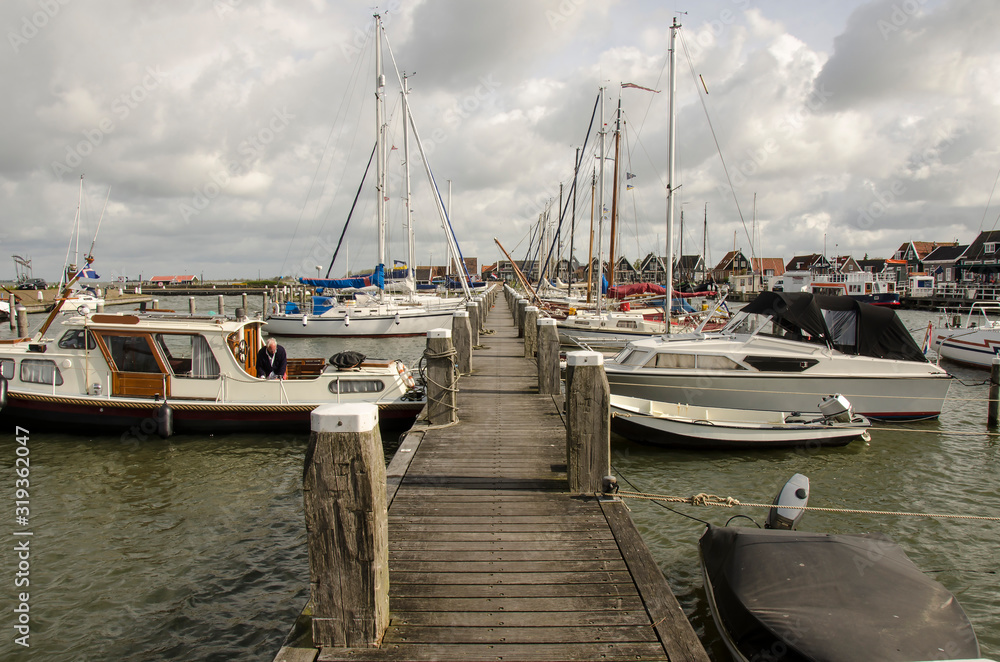 Fototapeta premium Boats on the pier, Marken, Netherlands. Beautiful pier of the island of Marken and typical wooden green houses near the waterfront in the fishing village.