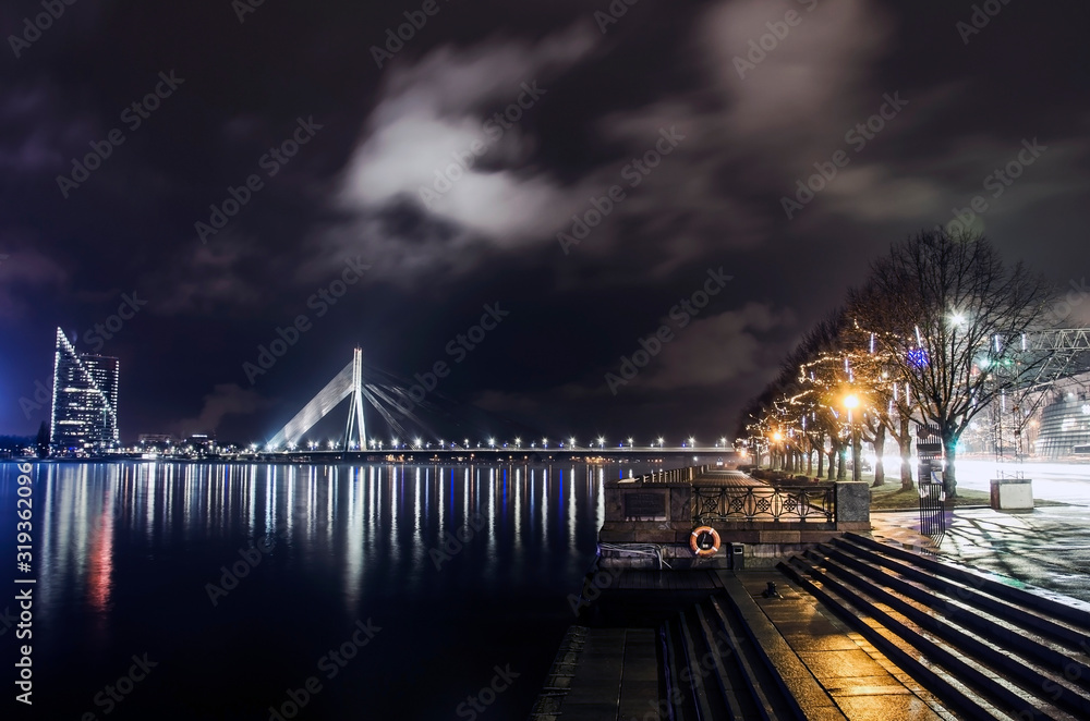 View of the cable-stayed bridge and river promenade with Christmas decoration in Riga at night, Latvia