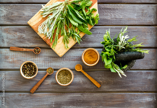 Herbs and spices on dark wooden kitchen desk top-down