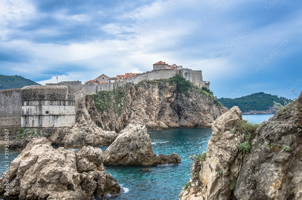 View of the fortress walls, rocky coast and blue sea, Dubrovnik, Croatia. Stunning view of Dubrovnik city walls and Dubrovnik old town, the famous Unesco world heritage site in Croatia.