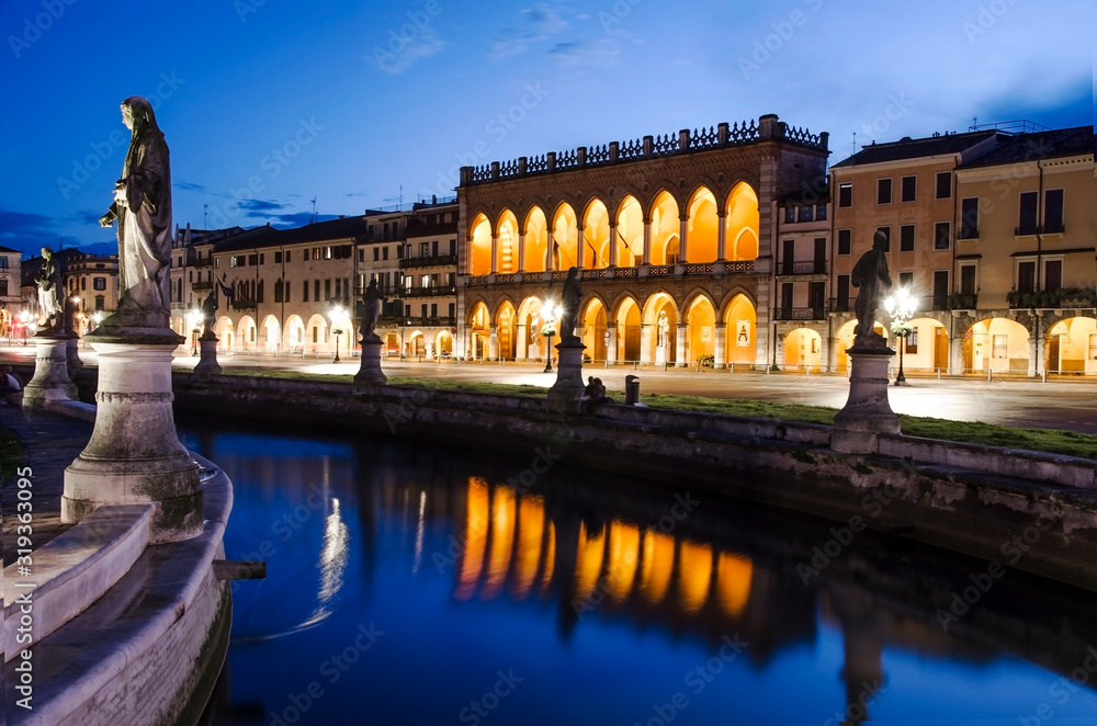 View of the canal with statues on square of Prato della Valle in Padova after sunset, Italy