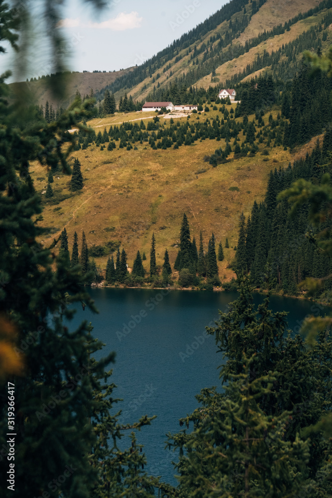 Fototapeta premium Kazakhstan, Kolsalsky lake. Mountain lake among pine forests in the evening light Kazakhstan, Kolsalsky lake. Lake in the mountains among pine forests in the evening light. On a hill stand at home