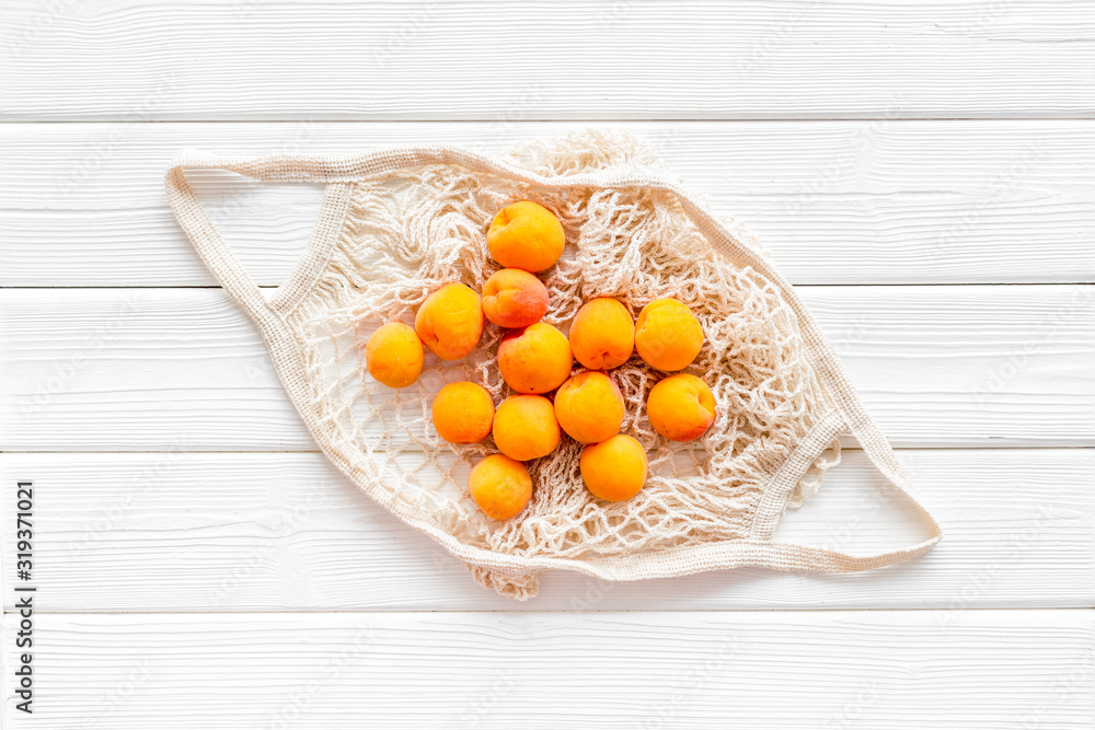 Eco-friendly package. Eco bag with fruits on white wooden background top-down Eco-friendly package. Eco bag with fruits on white wooden background top-down