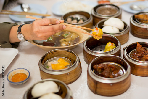 Bild auf Leinwand Hand holding chopsticks with steamed dumplings dim sum food in restaurant