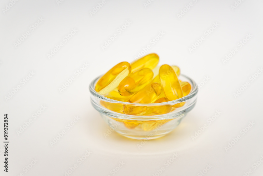 Fish oil supplement, medical and health concept, Soft gel capsules in glass bowl on white background