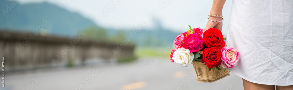 A beautiful woman wearing a white dress shirt standing, her carrying a basket of flowers-panoramic banner for web header A beautiful woman wearing a white dress shirt standing, her carrying a basket of flowers-panoramic banner for web header